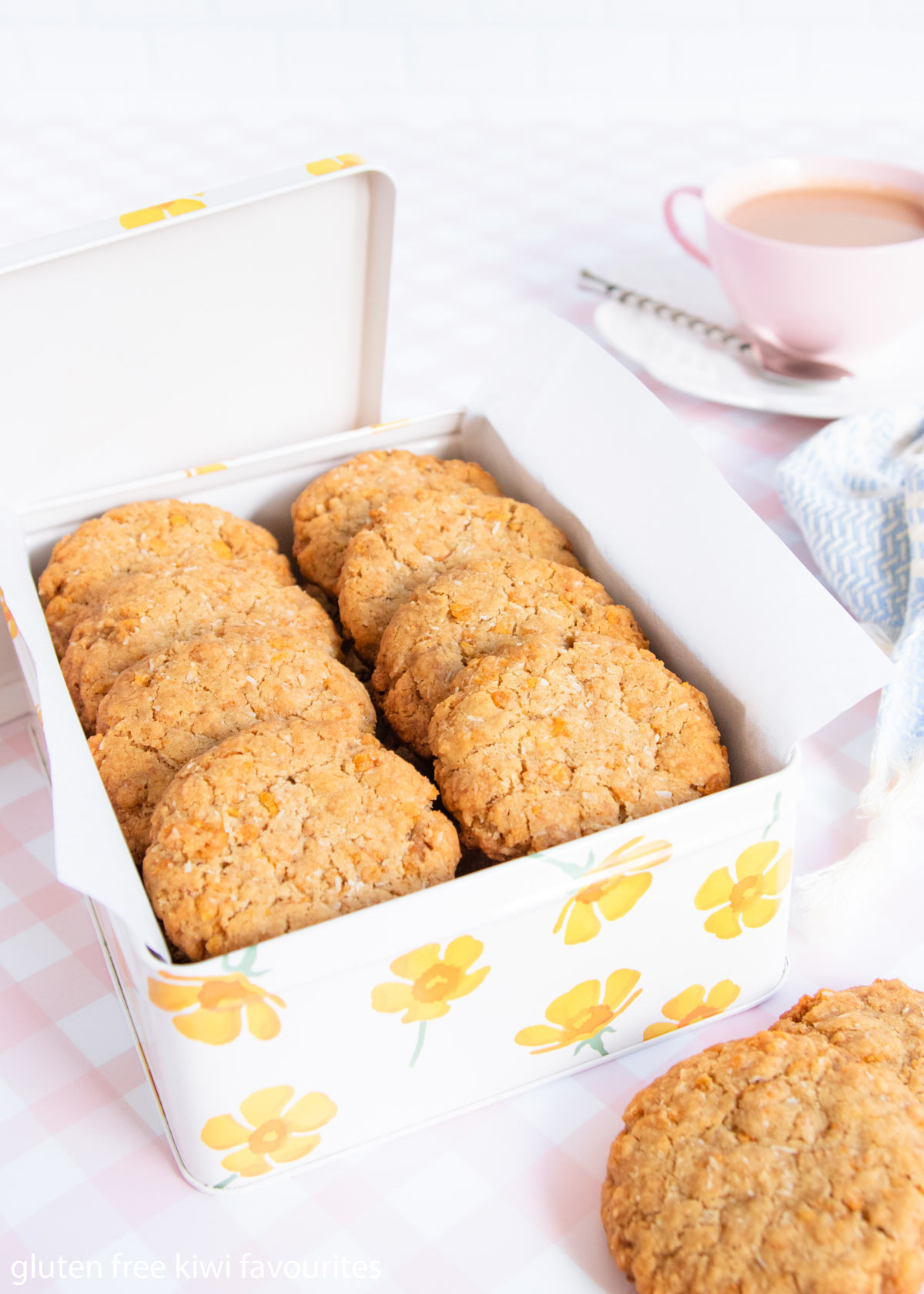 Anzac biscuits in a tin decorated with yellow flowers.