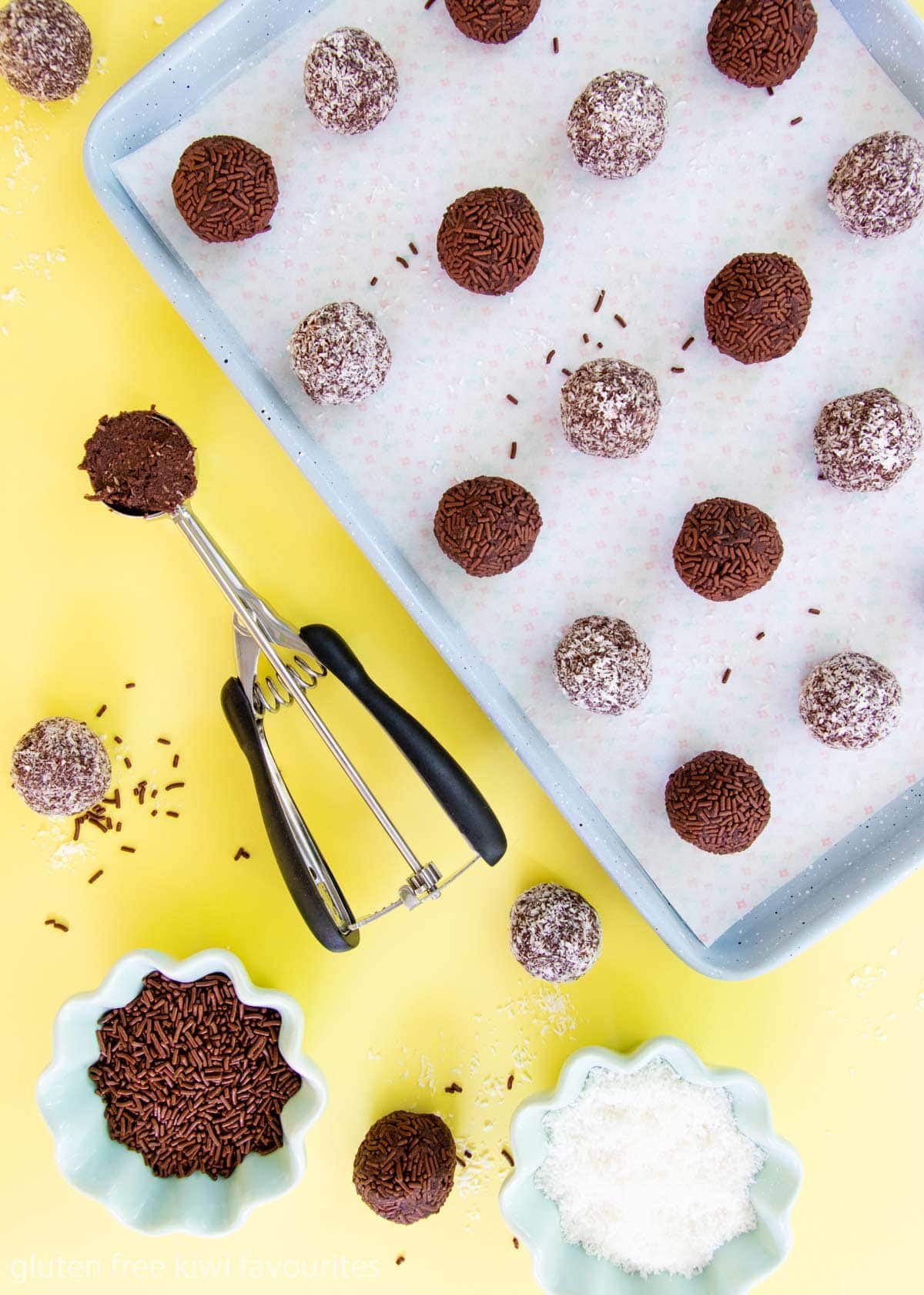 Rum balls being rolled in coconut and chocolate sprinkles.