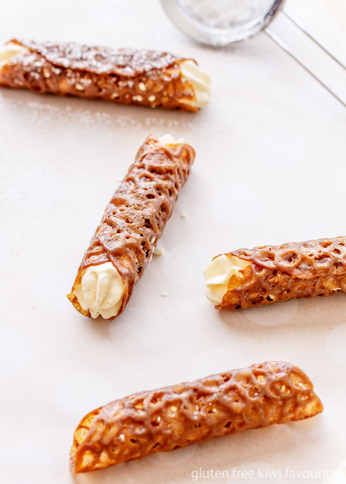 Three filled and one unfilled brandy snaps on a piece of parchment paper