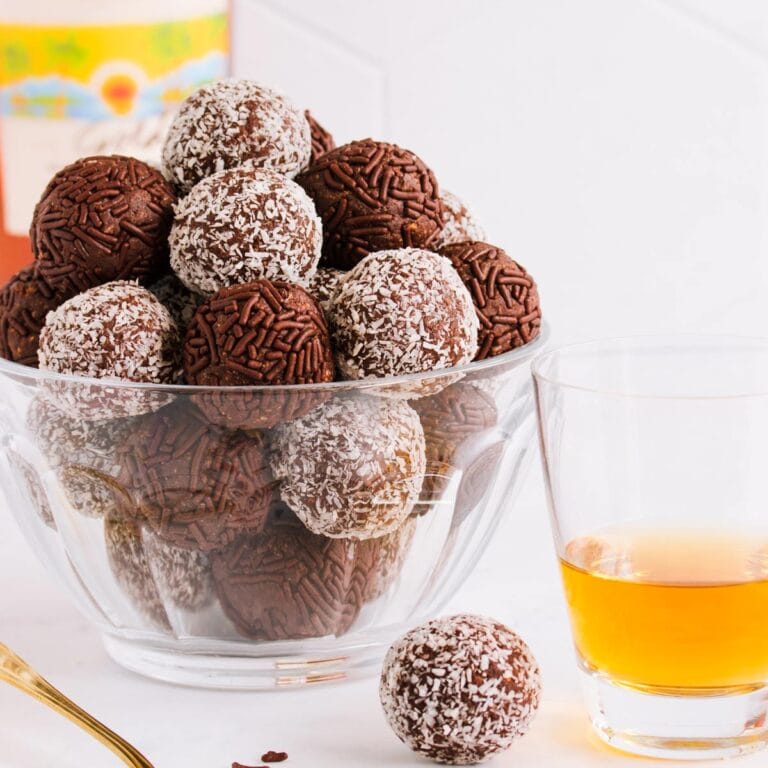 Gluten free rum balls in a white bowl on a yellow and blue background.