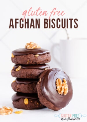A stack of five biscuits and a pale grey mug on a white tiled background, text overlay reads gluten free afghan biscuits.