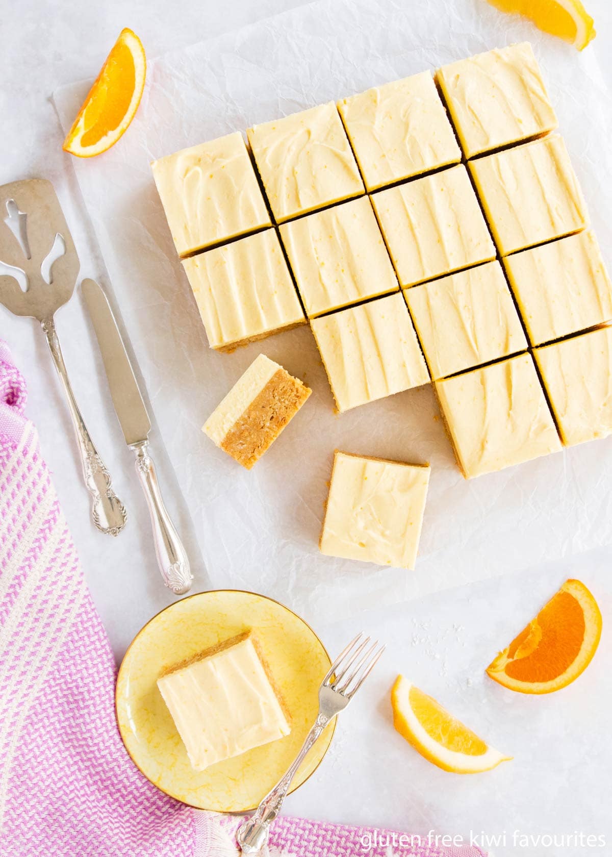 Citrus slice cut into squares, on a grey background with a purple napkin and slices of lemon and orange.