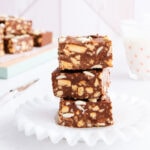 Three stacked pieces of gluten free chocolate slice on a white plate.