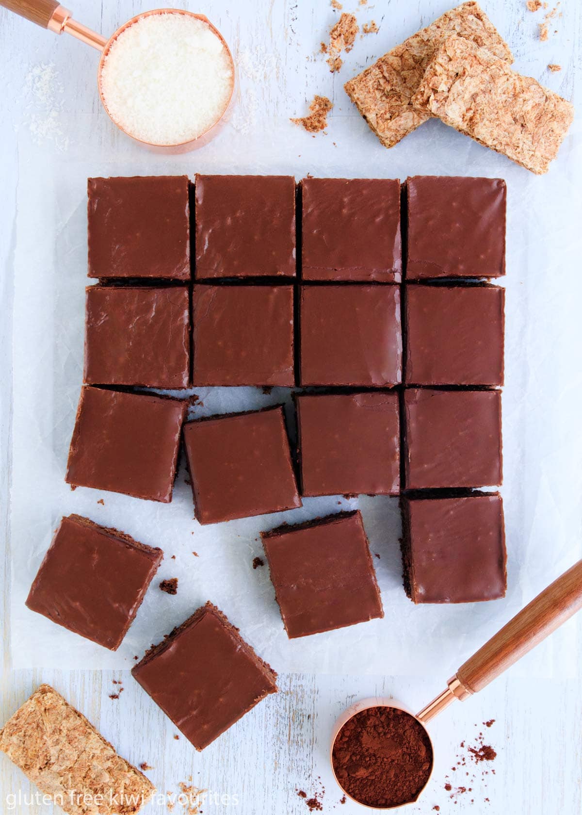 Overhead image of the slice with gluten free weetbix and measuring cups of coconut and cocoa around it.