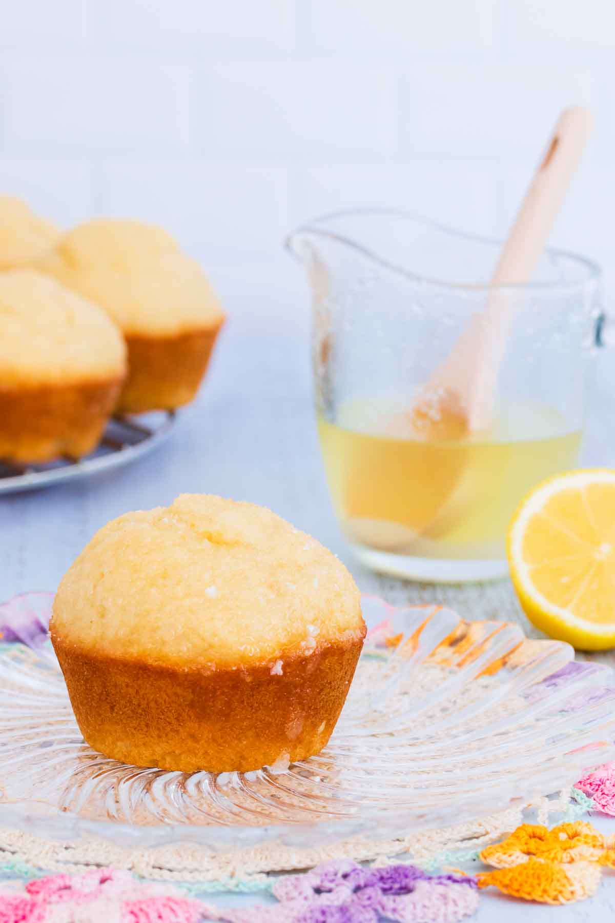 A muffin on a glass plate, with a blue background, text overlay reads "gluten free lemon muffins".