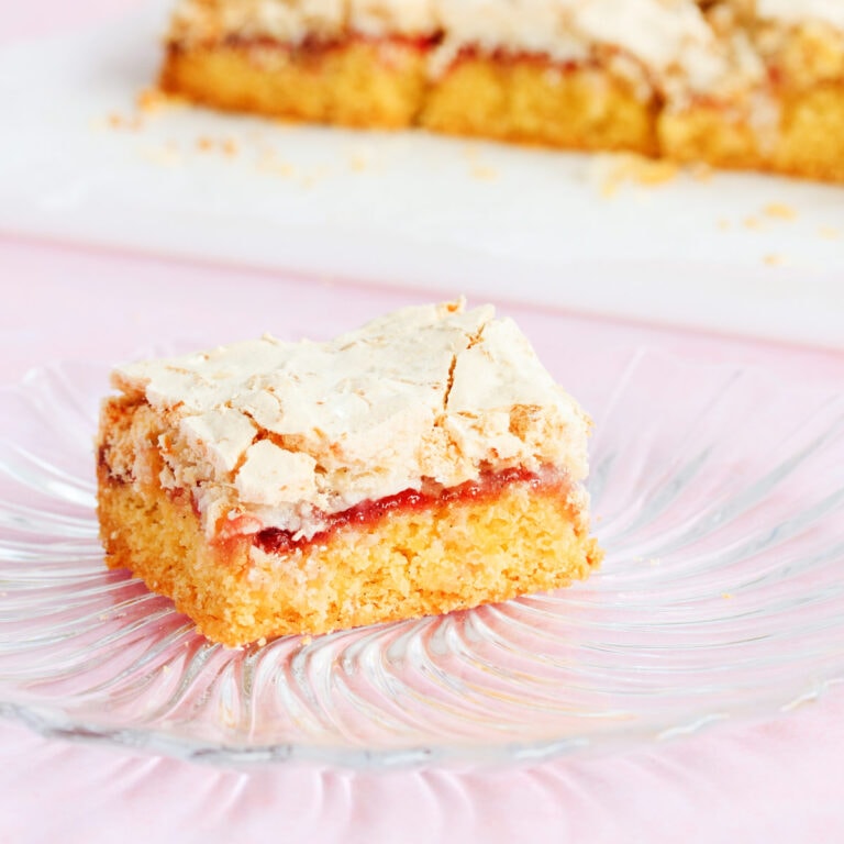One piece of Louise cake on a spiral rib textured glass plate on a pink background.