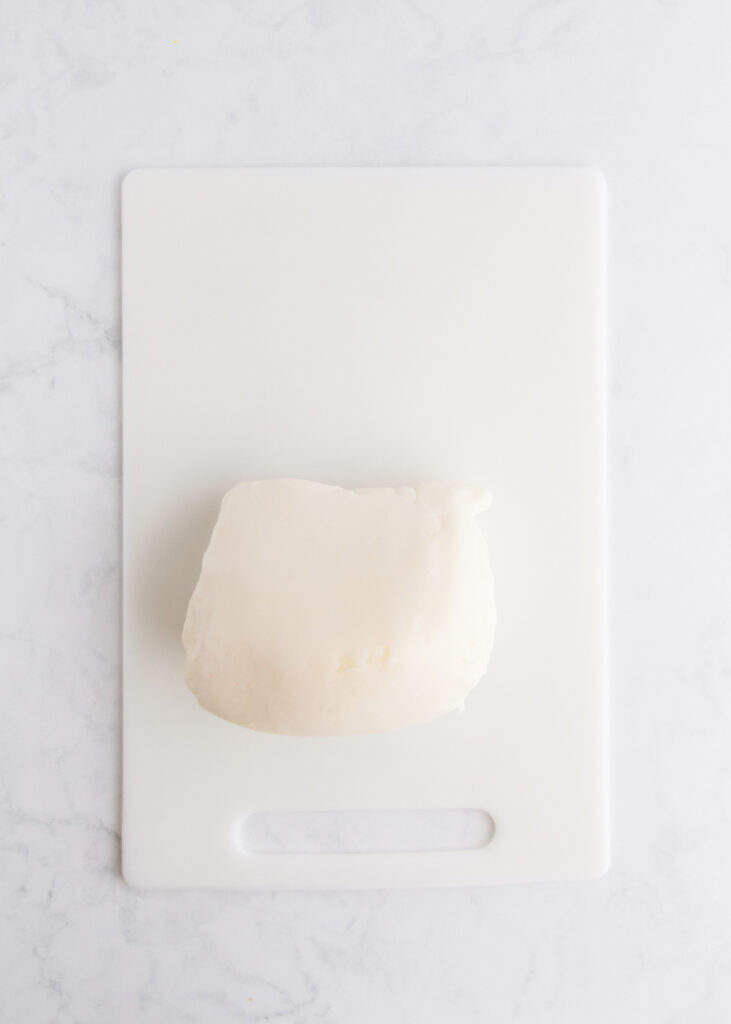 The ball of cooked playdough, on a white cutting board.