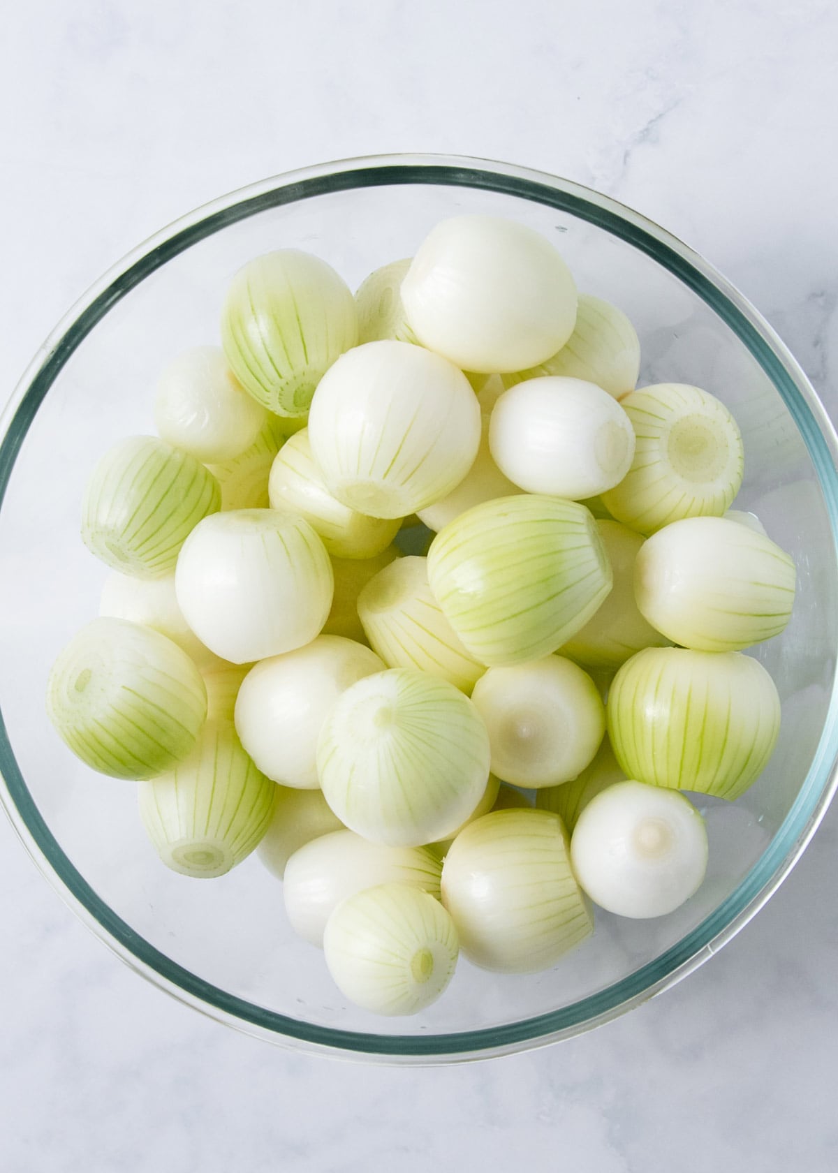 Peeled pickling onions in a glass bowl.