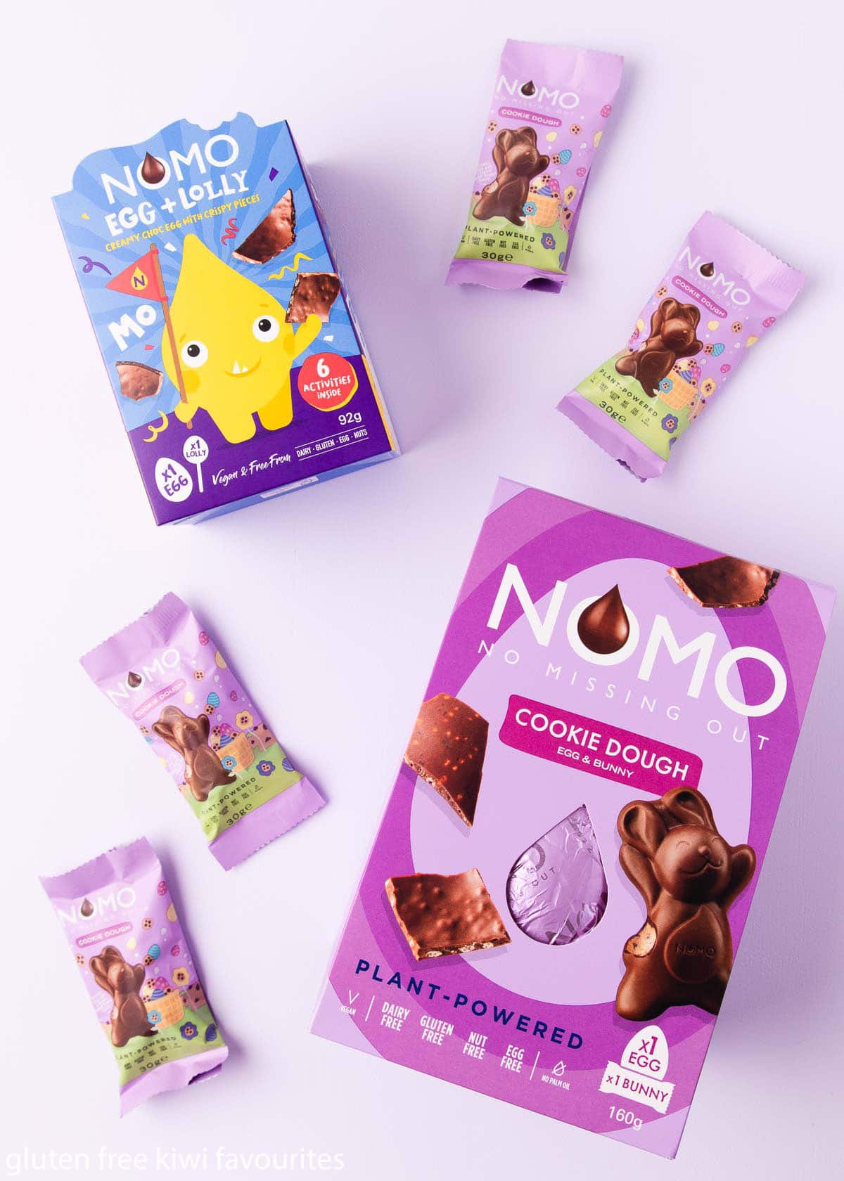 NOMO cookie dough egg and egg + lolly boxes on a light purple background.