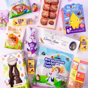 An assortment of different brands of gluten free Easter eggs and treats, on a mint green background.