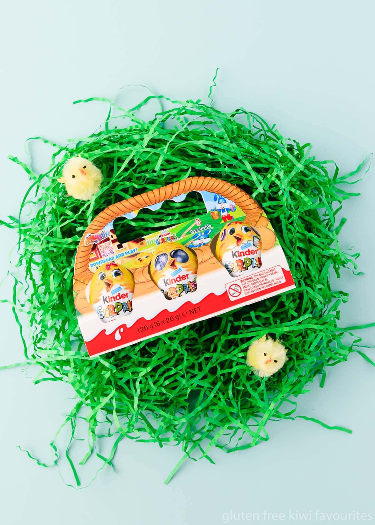 A 3-pack of Kinder Surprise Easter eggs, on a nest of green shredded paper.