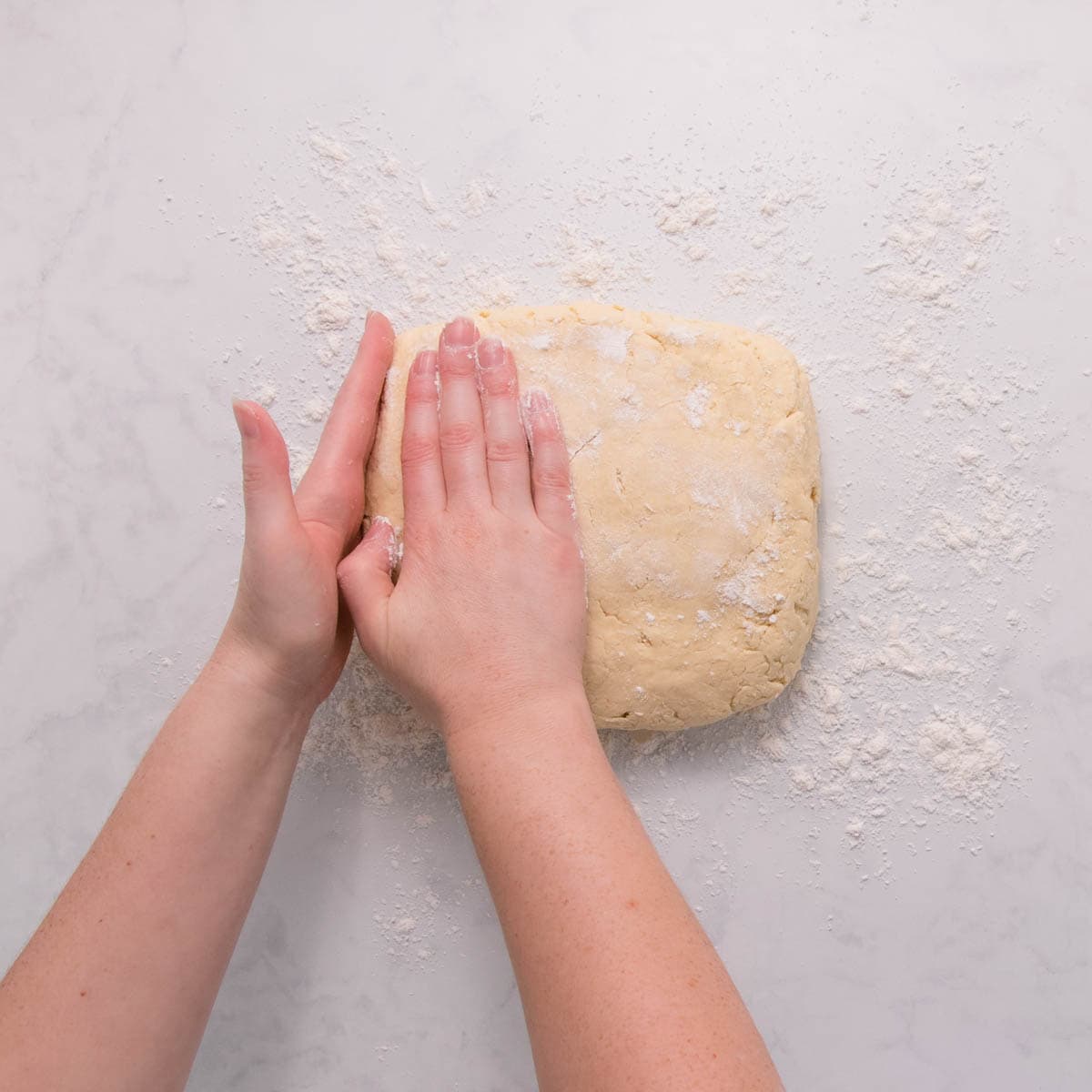 Hands shaping the dough into a square.