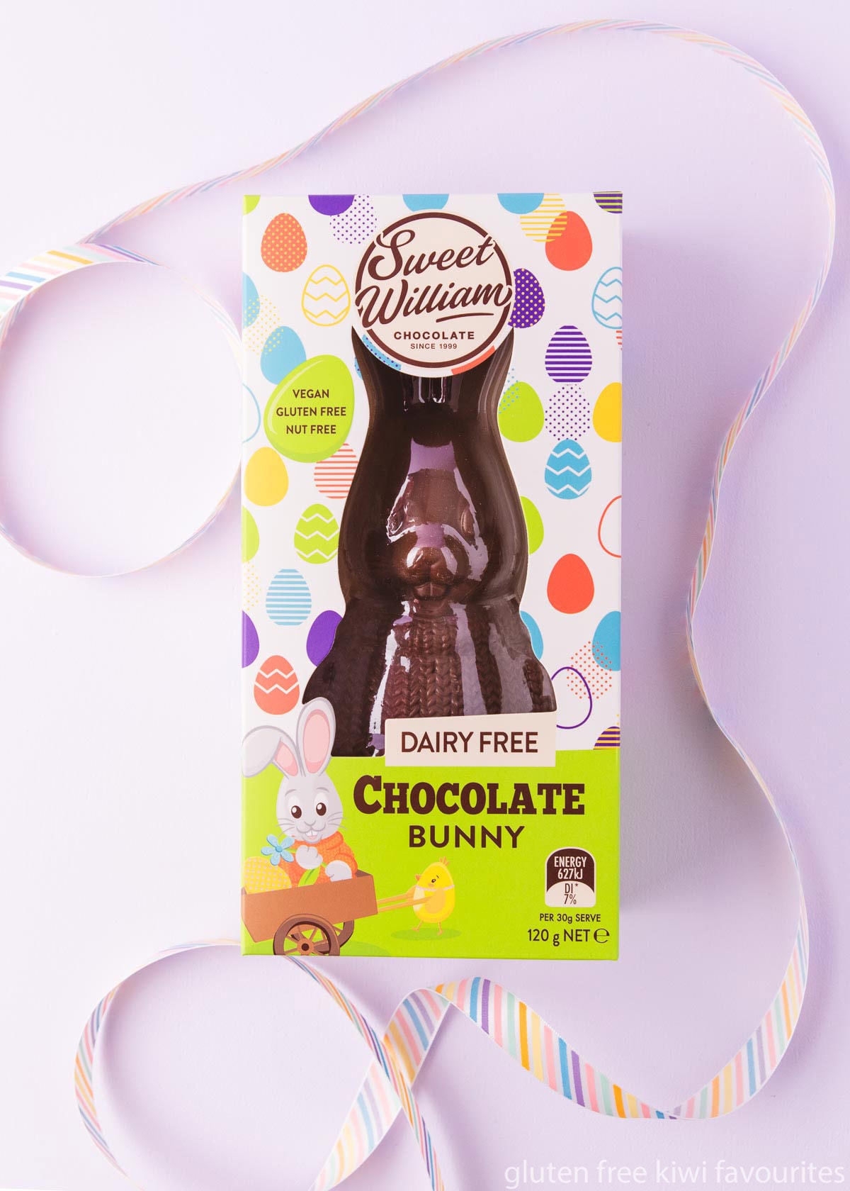 A Sweet William dairy free chocolate bunny in a colourful box on a light purple background.