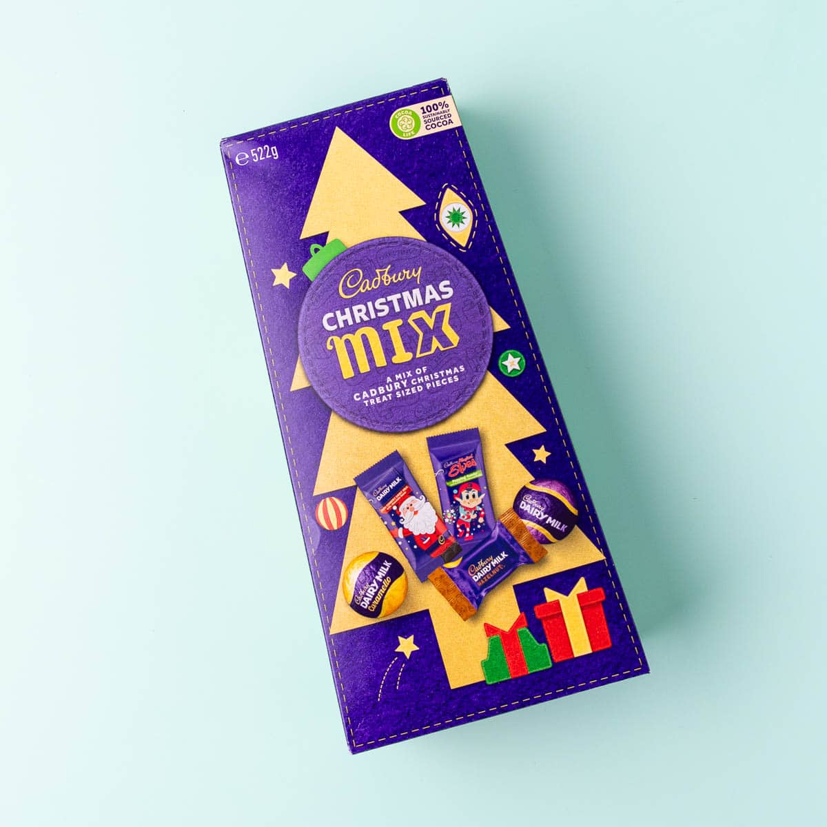 A purple box of Cadbury Christmas Mix chocolates  on a mint green background.