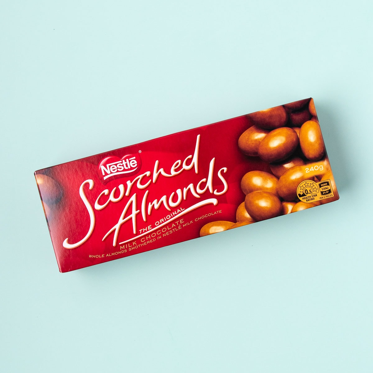 A box of Nestlé scorched almonds on a mint green background.
