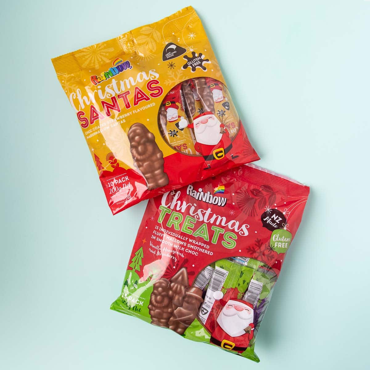 A bag of Rainbow brand marshmallow Santas, and Christmas Treats, on a mint green background.