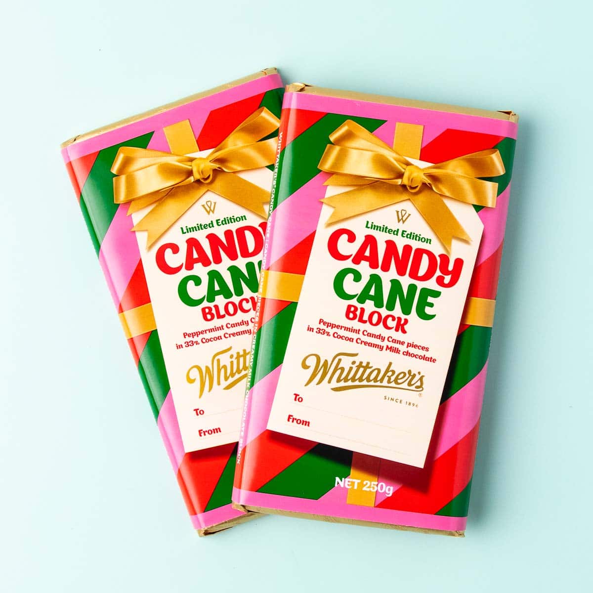 Two blocks of Whittakers Candy Cane 250g chocolate blocks in their festive wrappers, on a mint green background. 