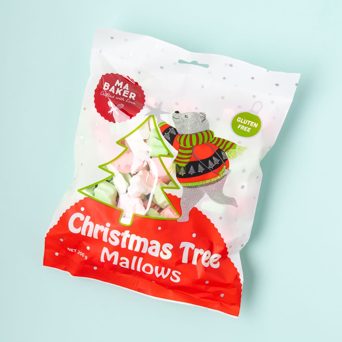 A white and red packet of Ma Baker Christmas tree-shaped marshmallows, with a clear tree-shaped window showing the pink, green and white marshmallows inside.
