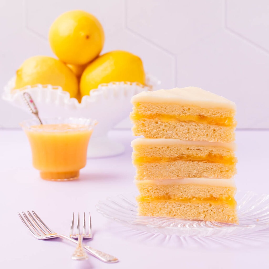 Three triangular pieces of lemon slice stacked on top of each other on a glass plate with a bowl of lemons in the background.