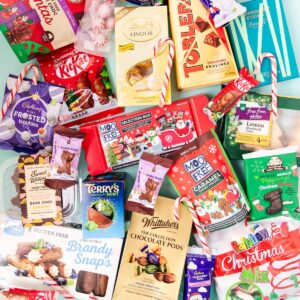 An assortment of gluten free Christmas chocolate and other sweet treats all jumbled together on a mint green background.