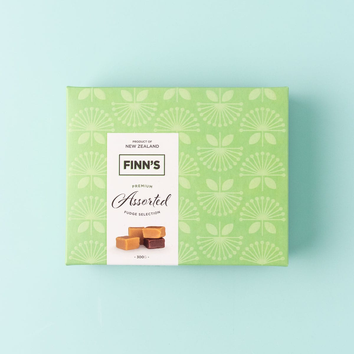 A light green box of Finn's Premium Assorted Fudge Selection, on a mint green background.