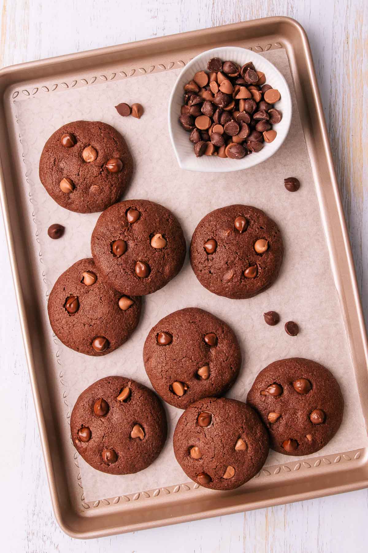 A tray of chocolate biscuits, with a small blue bowl of chocolate chips.