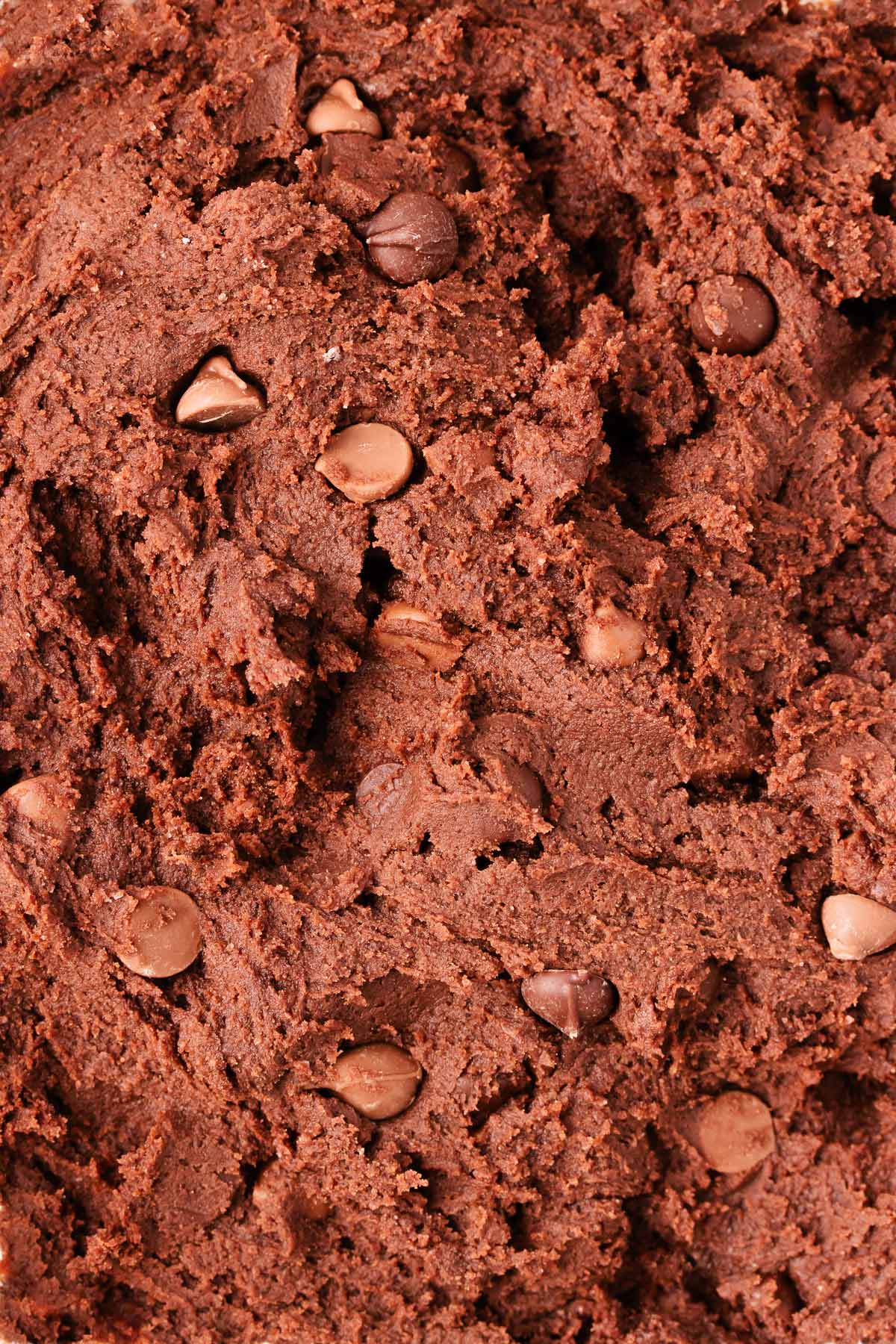 A close up of the chocolate biscuit dough, showing the rich dark brown colour and all of the chocolate chips.