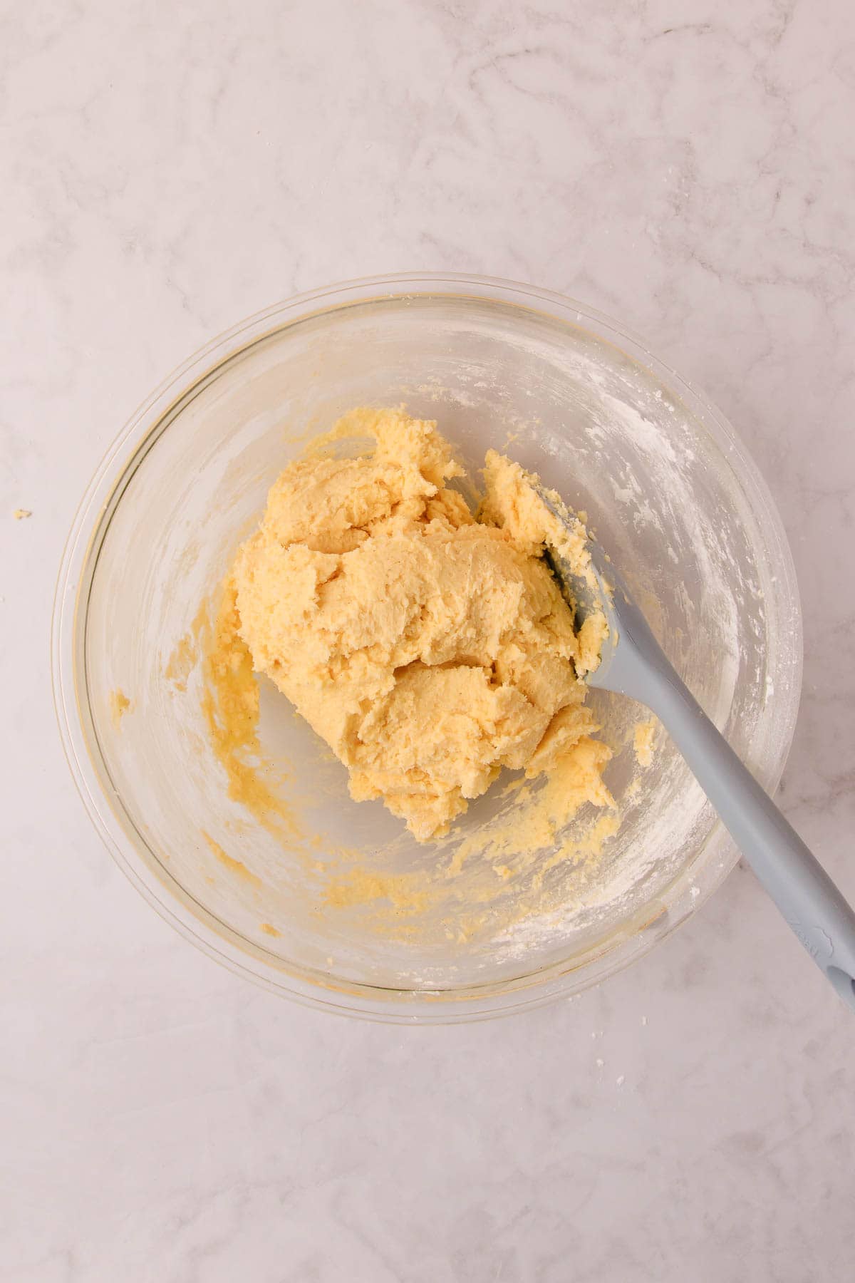 The biscuit dough after the flour has been stirred in with a blue silicone spoon.