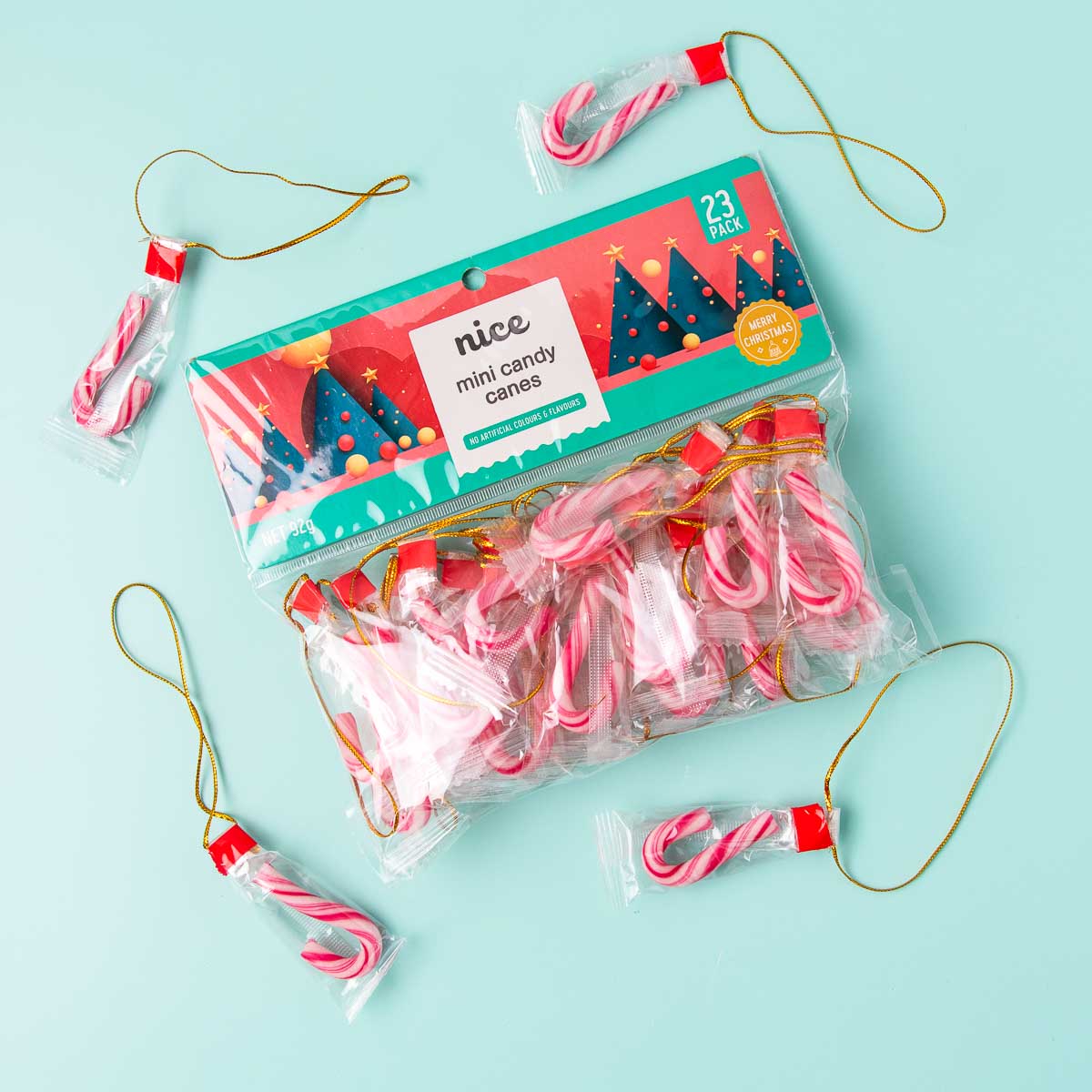 A packet of Nice brand mini candy canes. The candy canes are small and individually wrapped, and have a loop of gold string attached to each one.