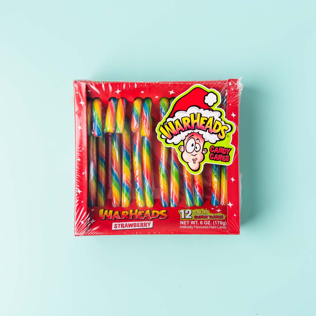 A box of Warheads sour strawberry candy canes. The candy canes are rainbow striped and in a red box.