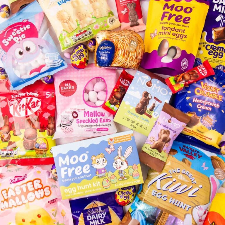 An assortment of different brands of gluten free Easter eggs and treats on a pink background.